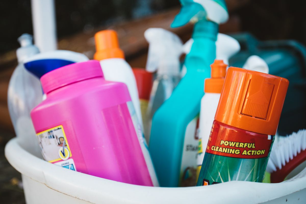 Bucket filled with household cleaning sprays, cloths and brushes ready for a job
