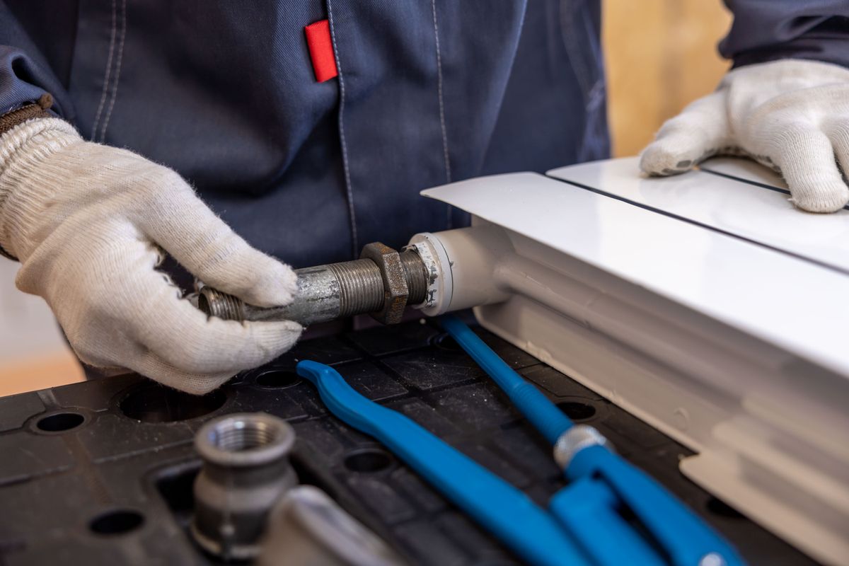 Plumber fitting a radiator pipe with specialist tools during a heating job