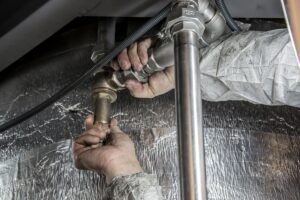 Plumber's hands fitting steel water pipes together during a home repair job