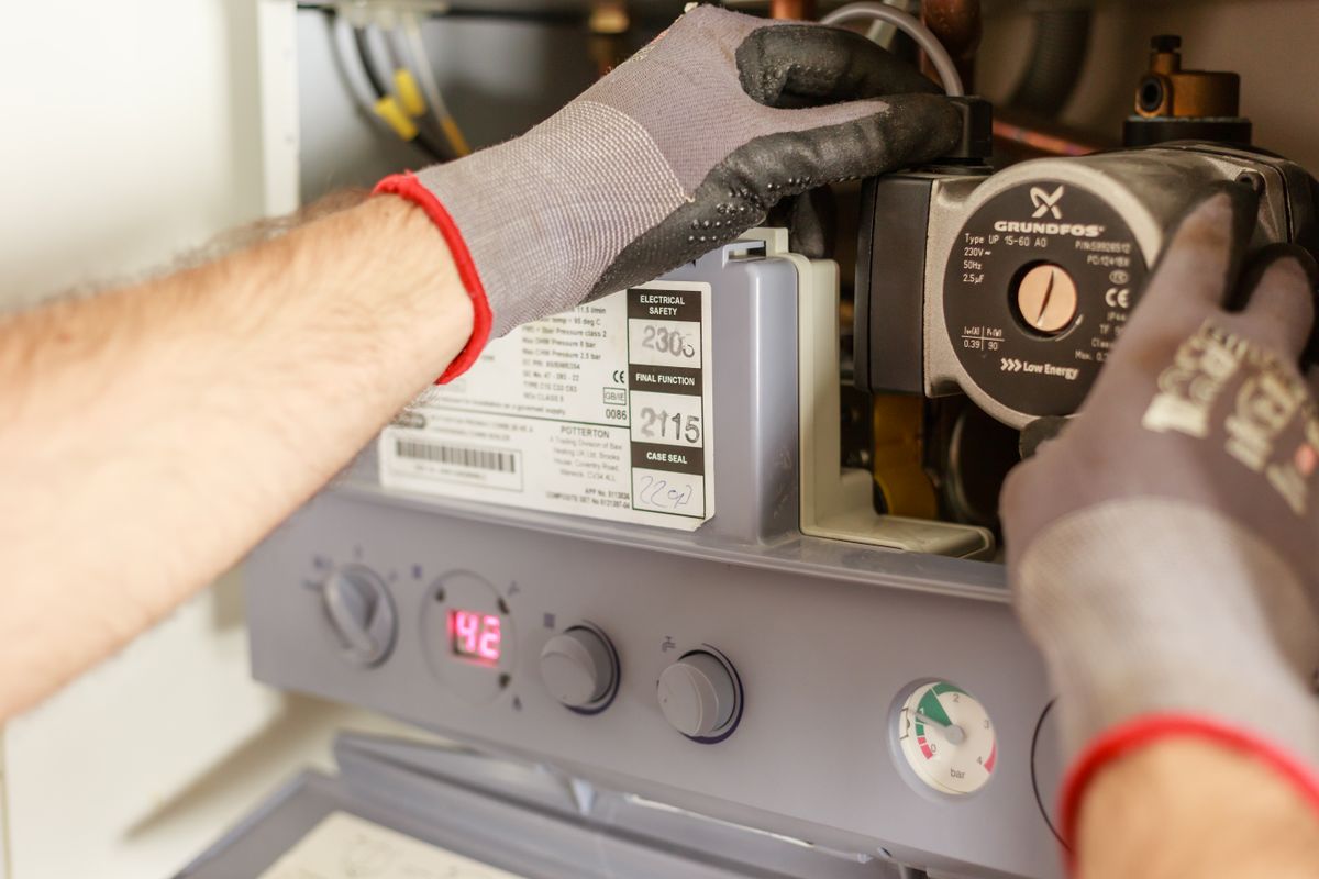 Plumber adjusting the controls and pipework on a domestic boiler unit
