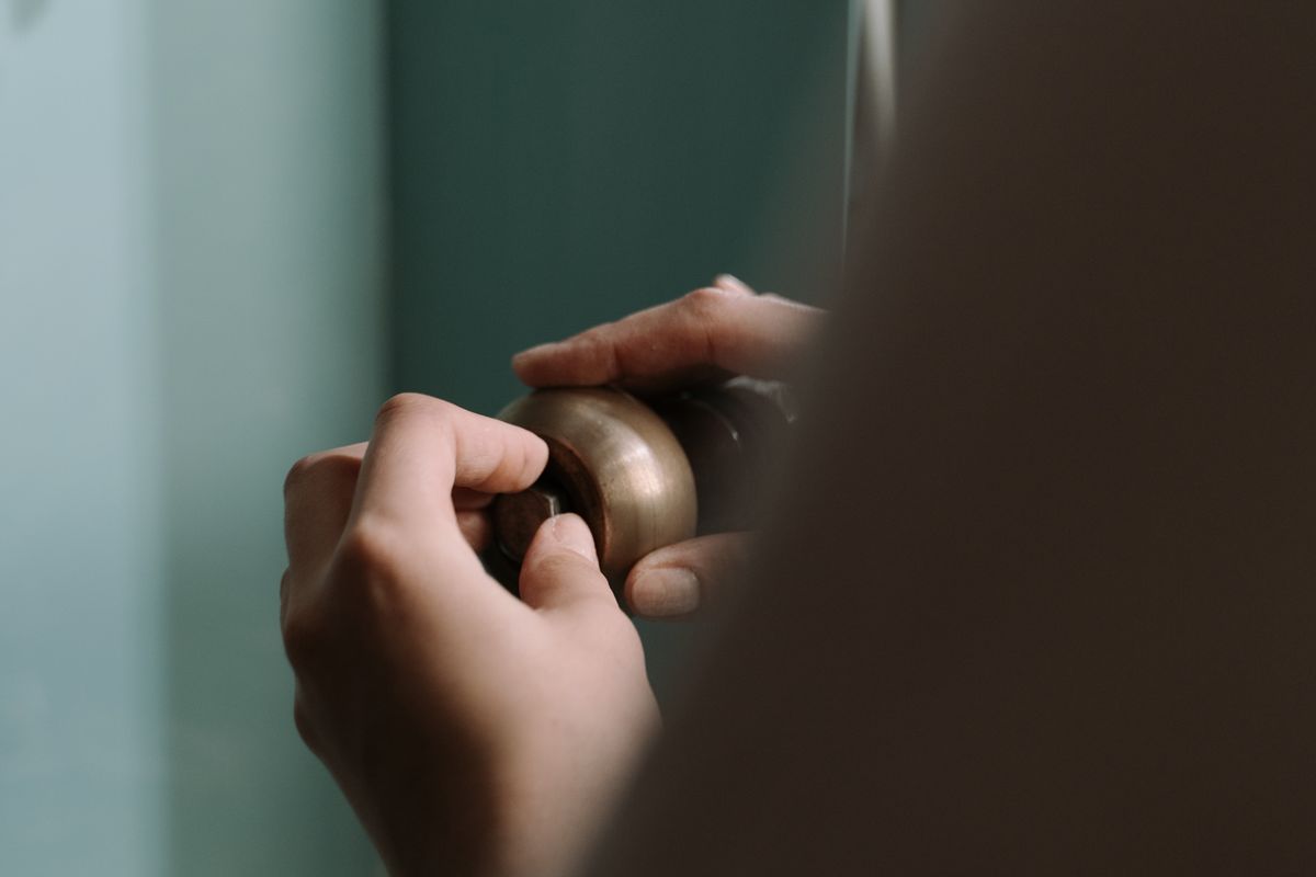 Close-up of hands tightening a drain pipe fitting under a kitchen sink cabinet