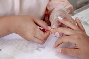 Nail technician applying acrylic to a client's nail during an extension appointment