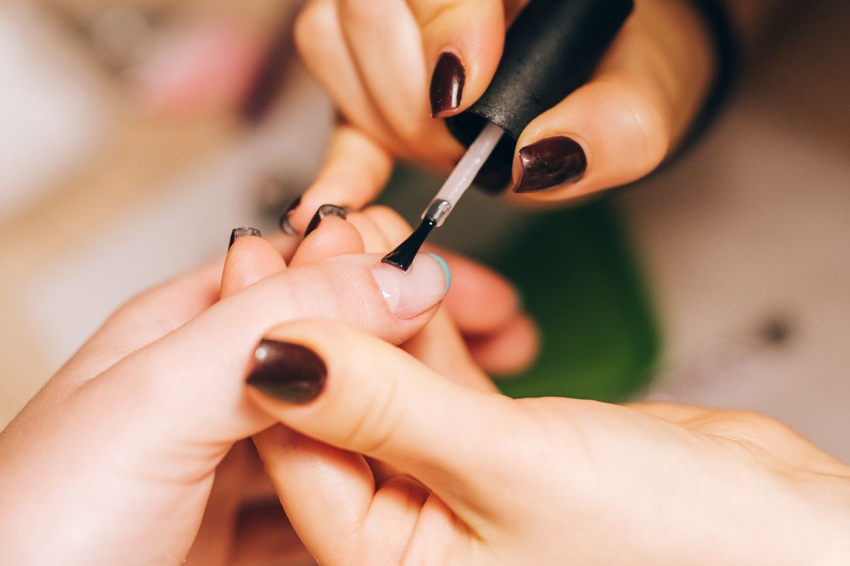 Manicurist carefully applying nail polish to a client's hand in a salon