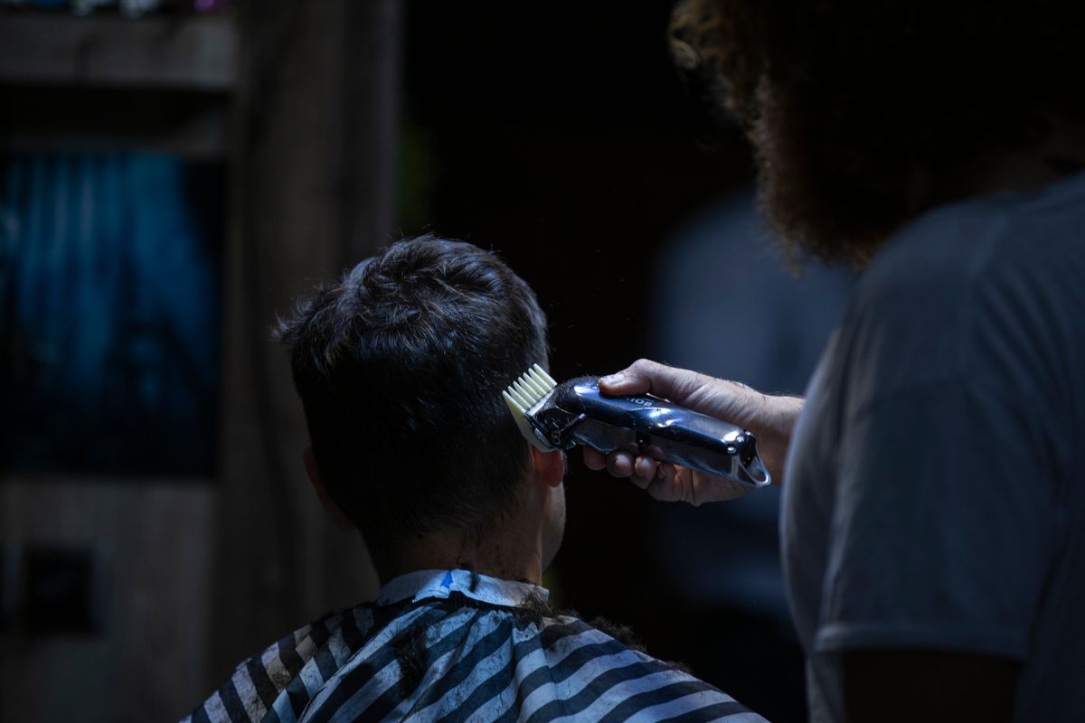 Barber using electric clippers to shape a client's haircut