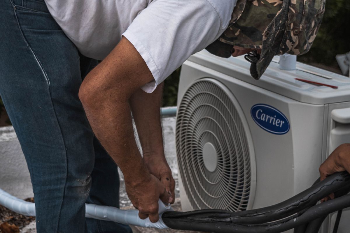 Technician checking hose and line connections on an outdoor air conditioning unit