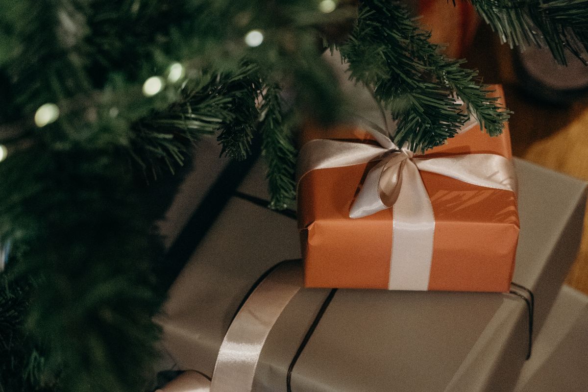 Person wrapping Christmas gifts with paper and ribbon