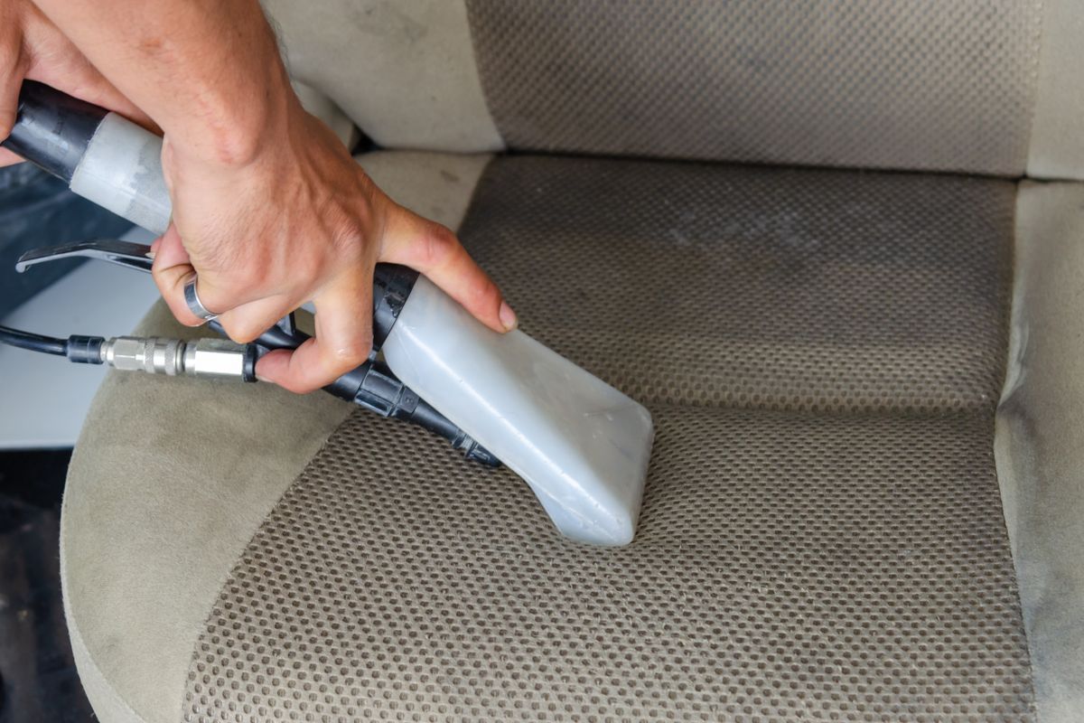 Deep cleaning an upholstered car seat during an interior detail