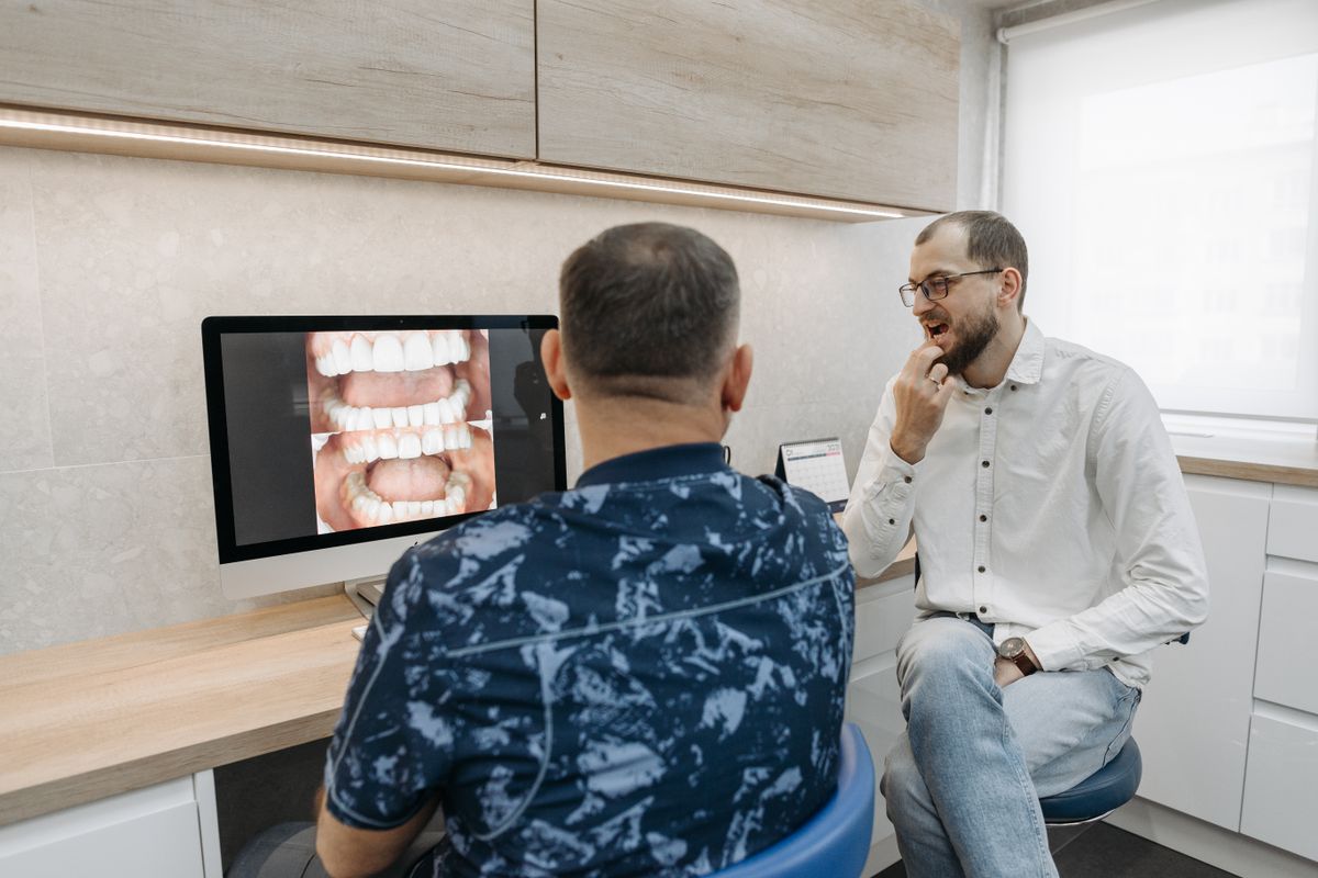 Dentist showing a patient their X-ray on a monitor while explaining treatment options