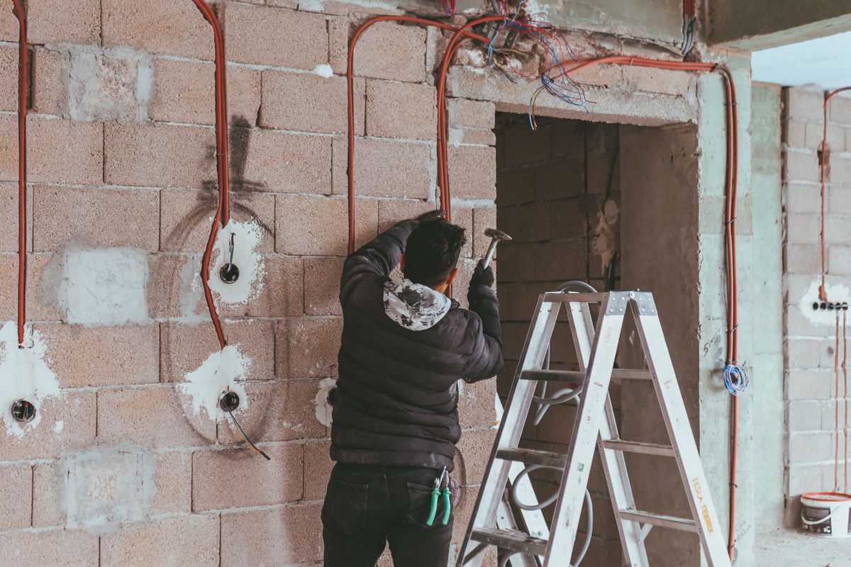 Electrician installing new wiring through a wall during a home renovation