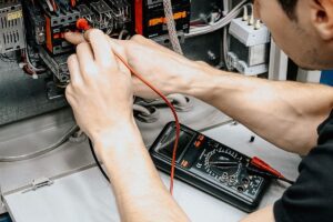Electrician using a multimeter to test connections inside a home electrical panel