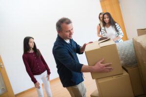 Family standing beside a pile of packed cardboard boxes in an empty room