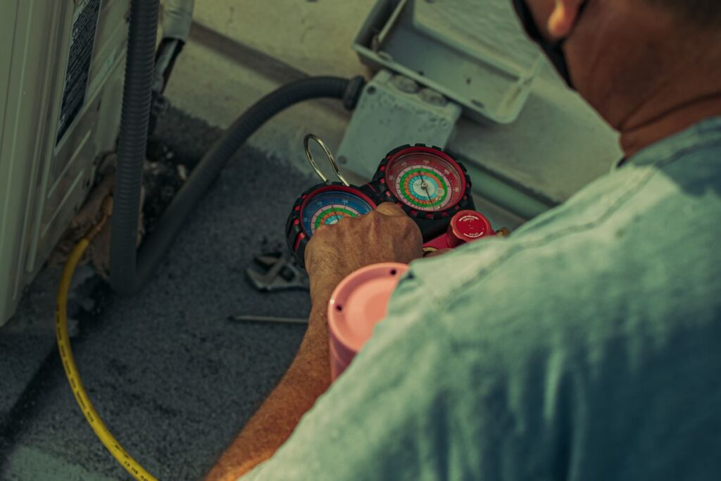 HVAC technician using gauges and tools to service an outdoor air conditioning unit