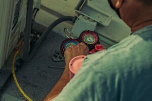 HVAC technician using gauges and tools to service an outdoor air conditioning unit