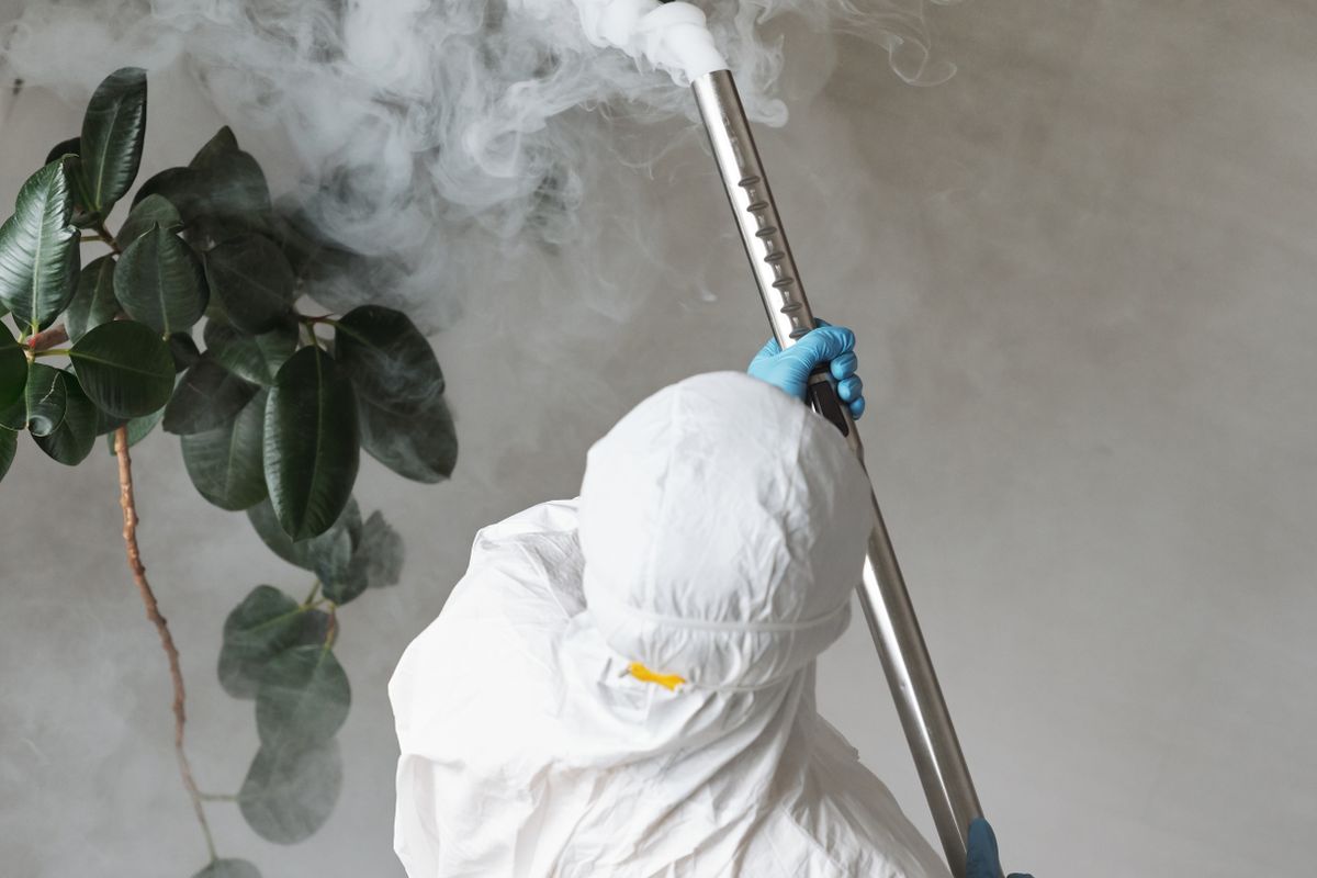 Technician in protective equipment using spraying gear for an indoor pest treatment
