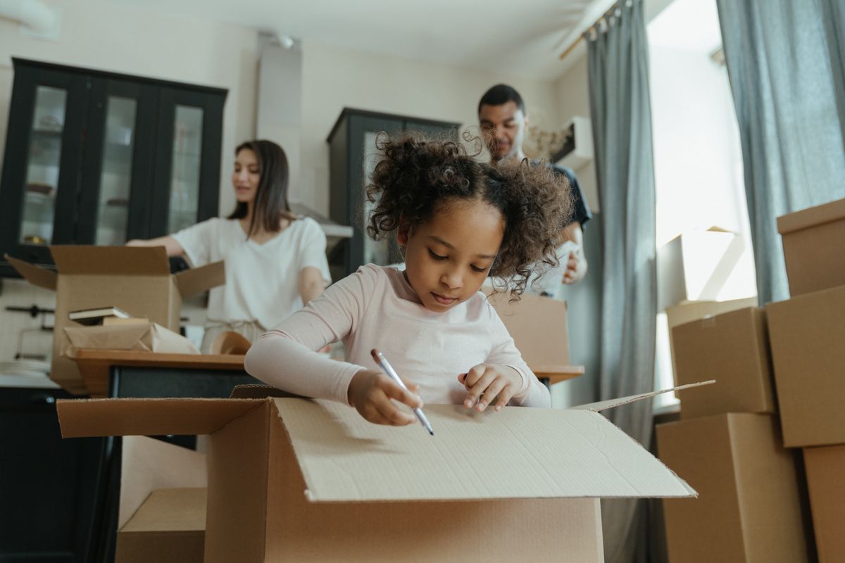 Person writing a label on a packed cardboard box before moving day