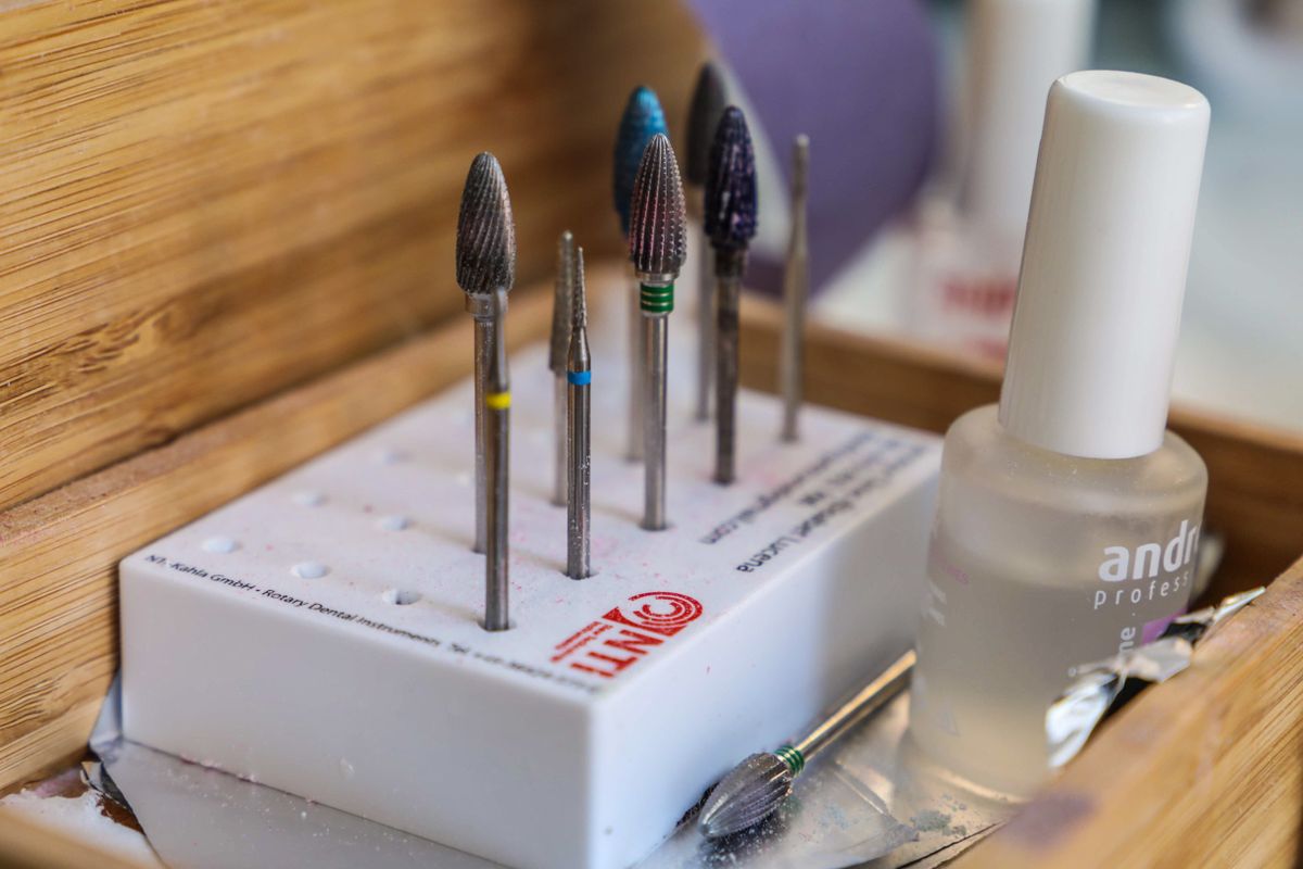 Close-up of manicure implements and electric file drill bits laid out for use