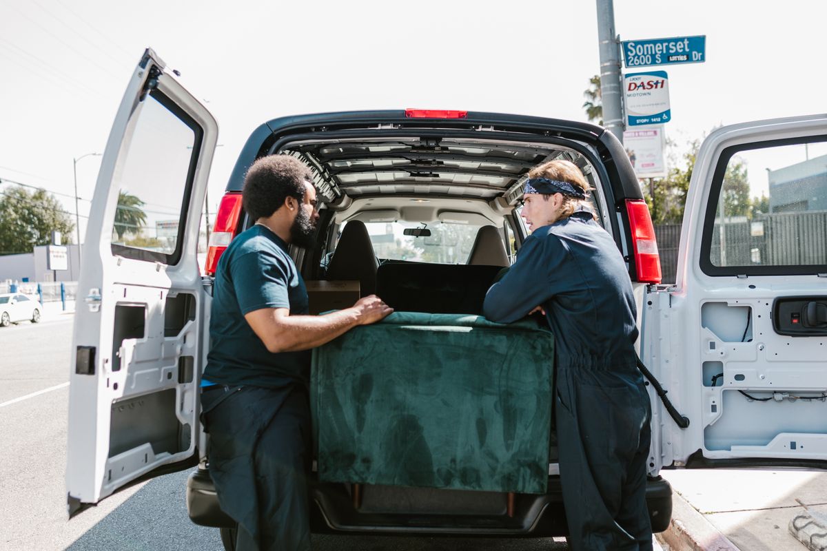 Two movers loading furniture into the back of a van during a house move