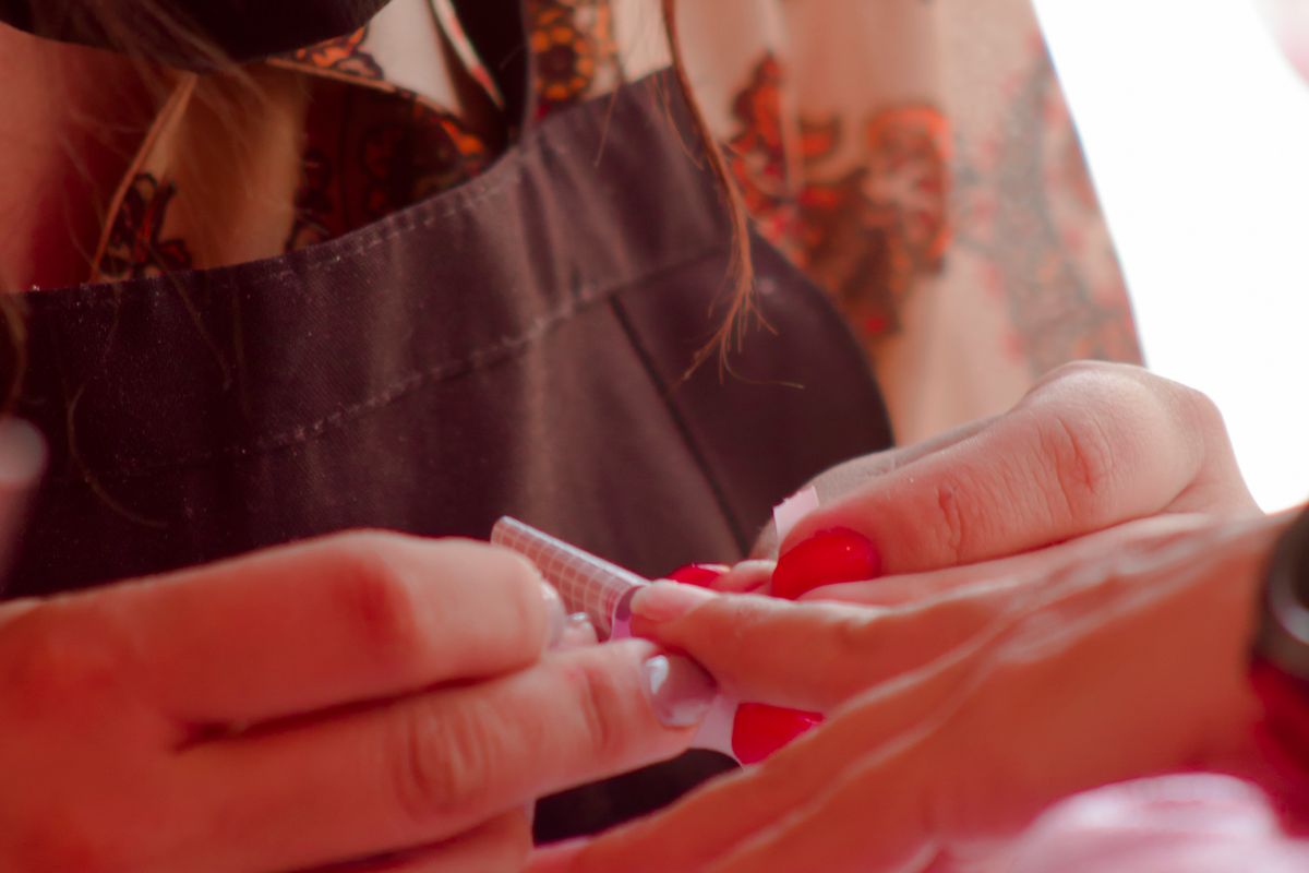 Close-up of a beautician carefully applying nail extensions in a salon