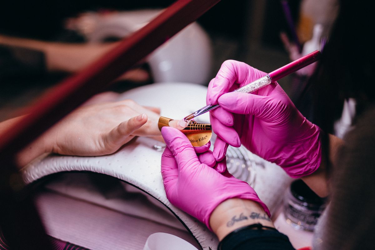 Nail technician using a fine brush during a nail treatment in a salon