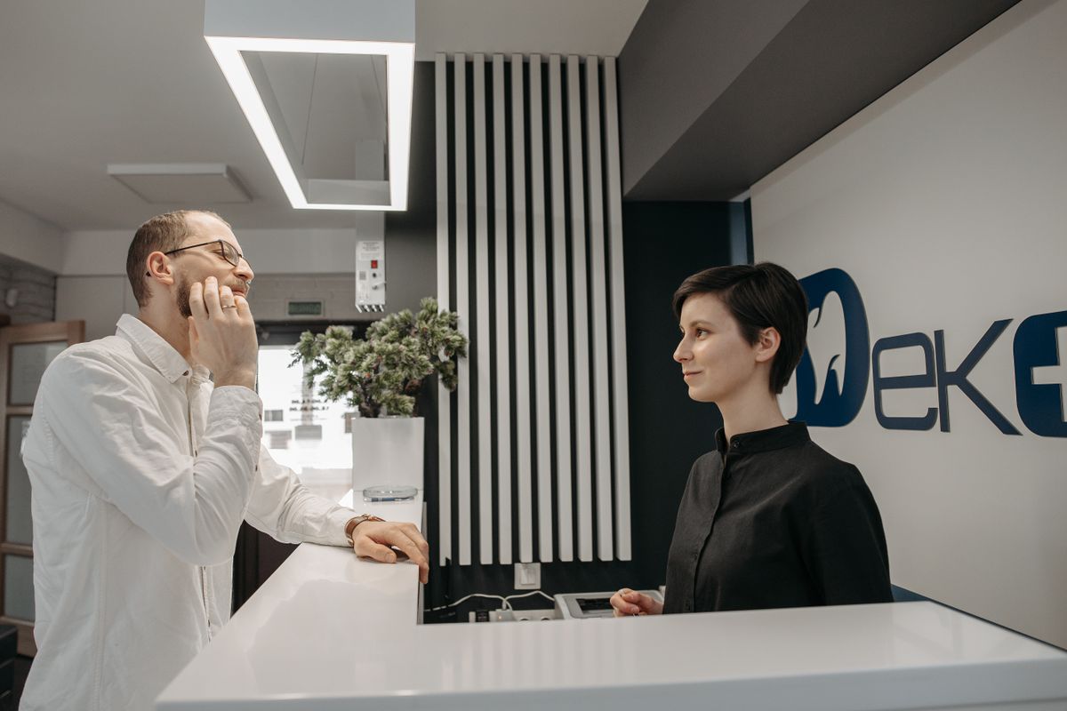 Patient speaking with a receptionist at the front desk of a dental practice