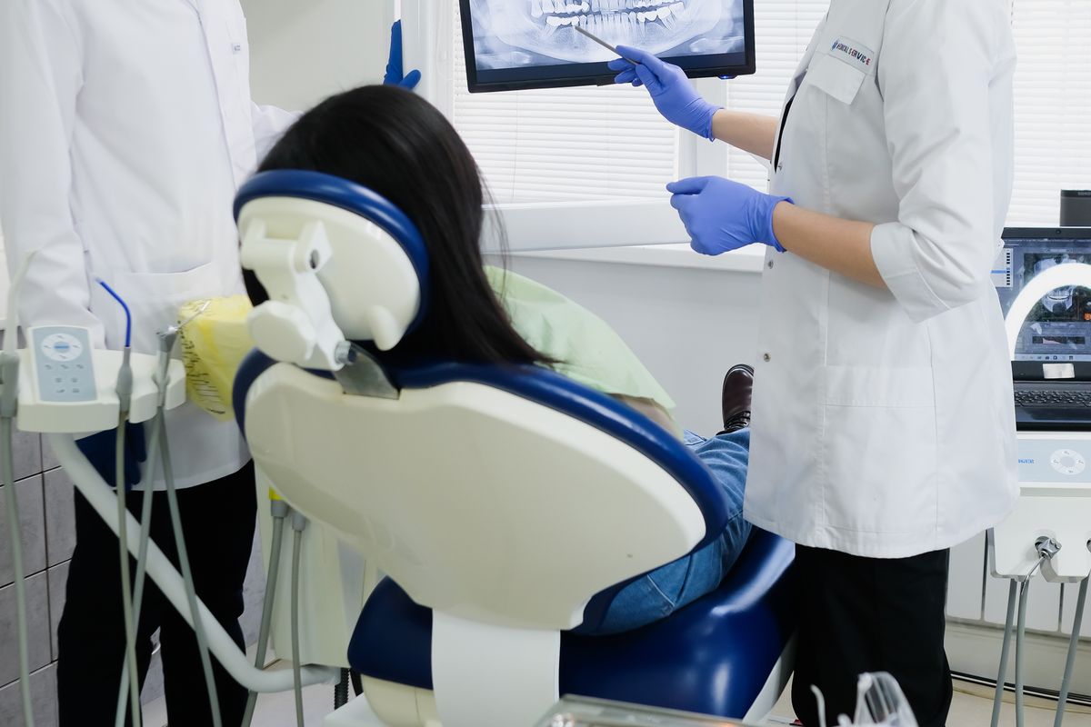 Dental team reviewing an X-ray on screen while discussing treatment with a patient