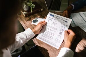 Person reading through a financial document at a wooden desk in daylight