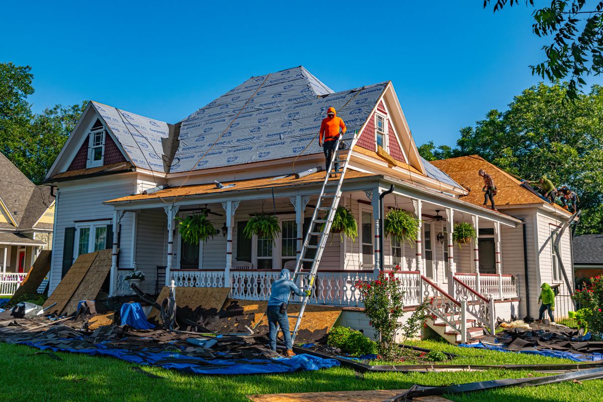 Workers stripping and replacing the roof of an older residential property