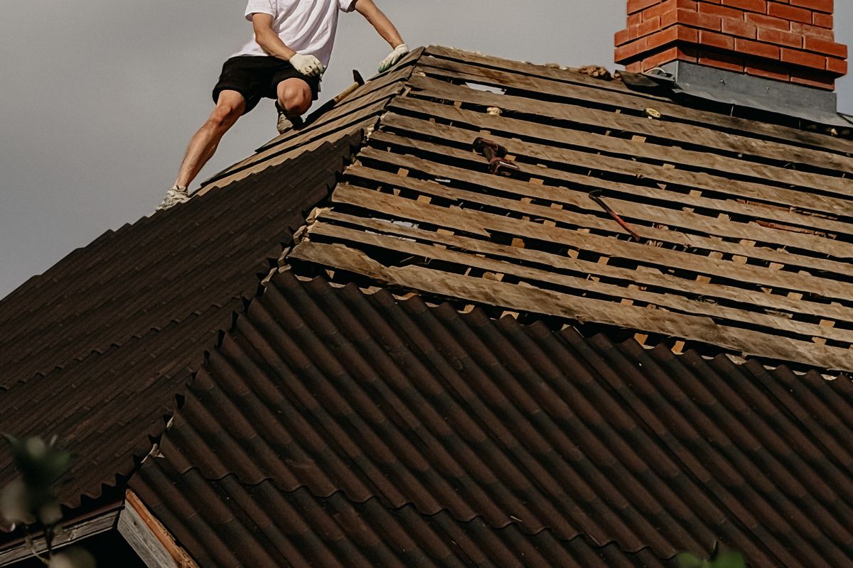 Roofer wearing a safety helmet repairing the roof of a brick house