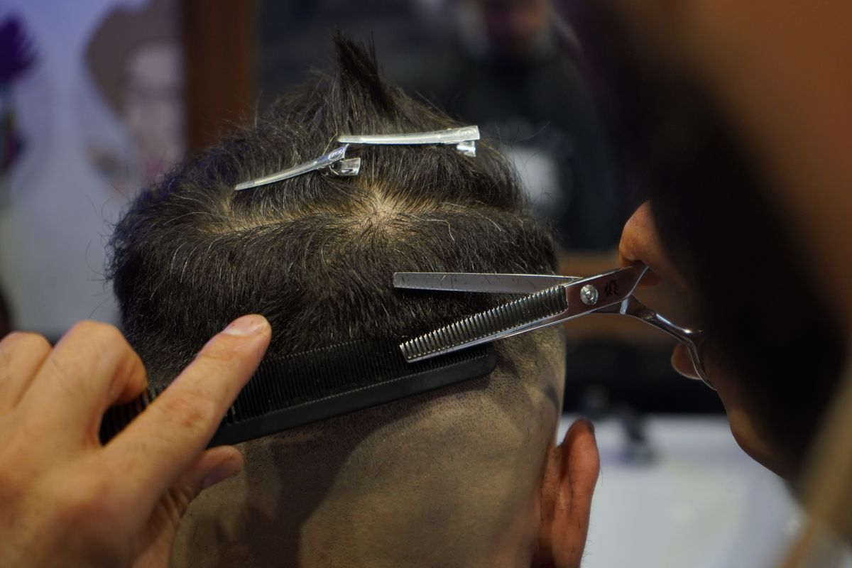 Close-up of scissors and comb being used during a haircut
