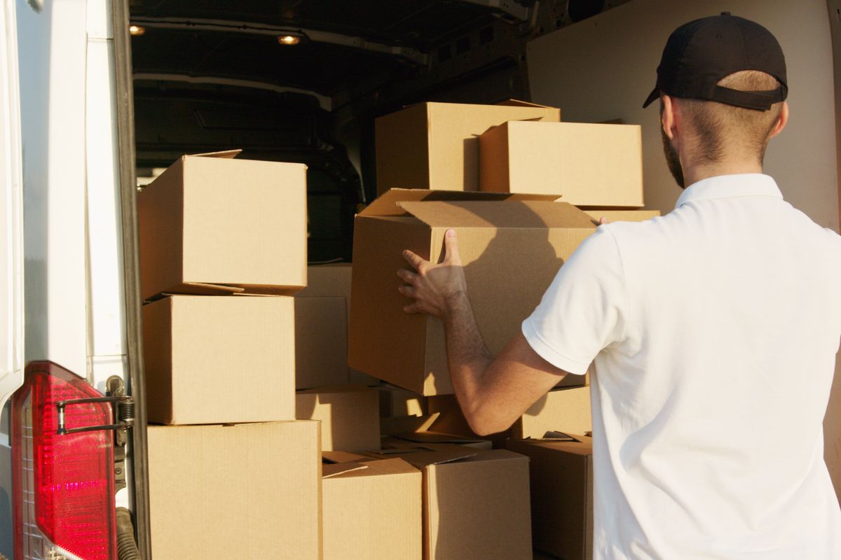 Worker carefully stacking cardboard moving boxes inside a van