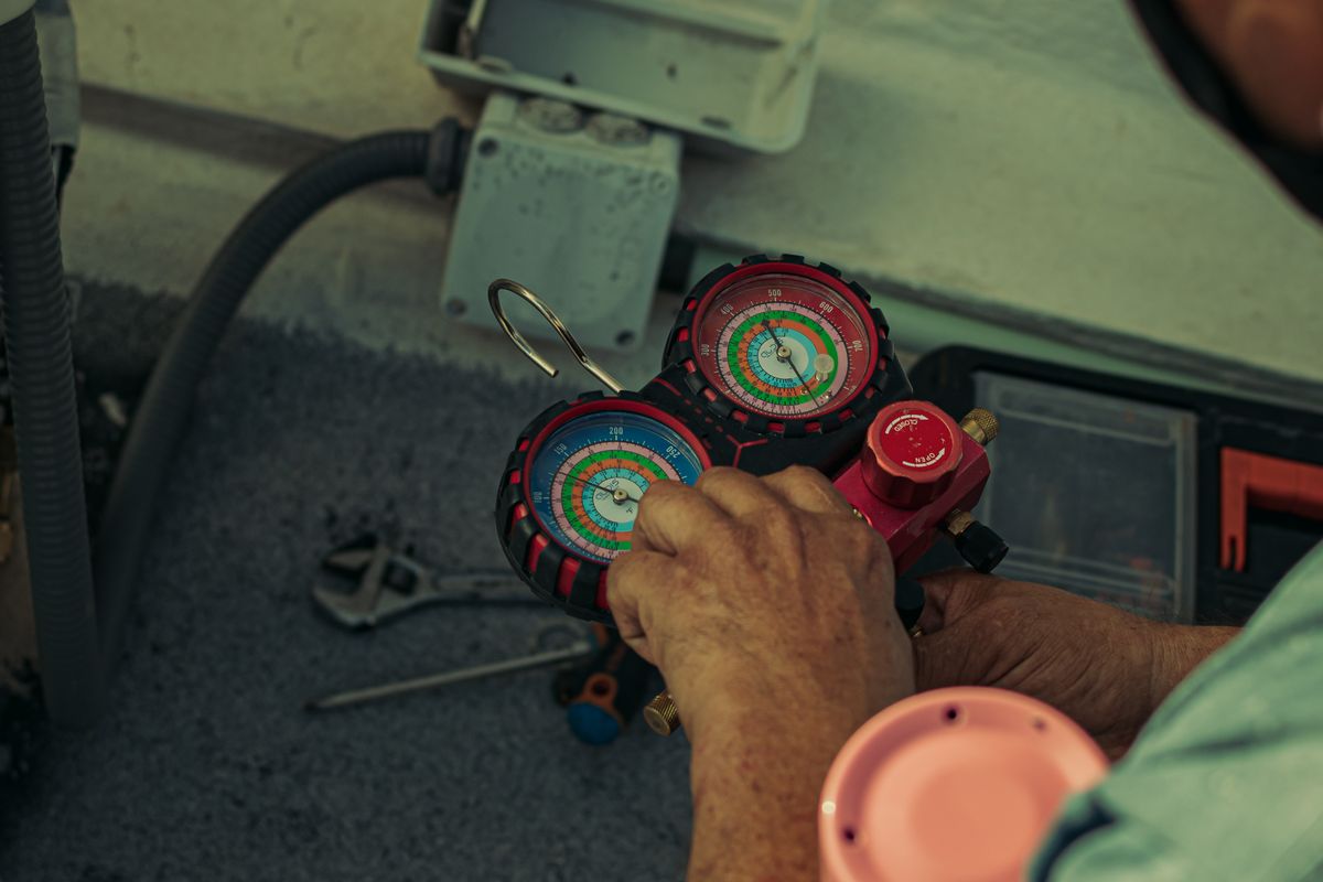 Technician reading refrigerant manifold gauges during an air conditioning service
