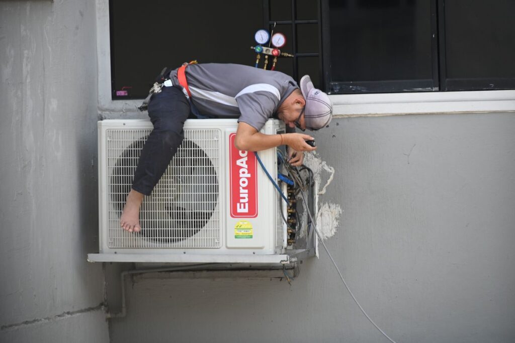 HVAC technician working on an air conditioning unit mounted outside a home