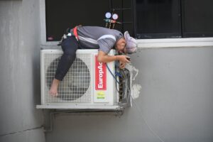 HVAC technician working on an air conditioning unit mounted outside a home