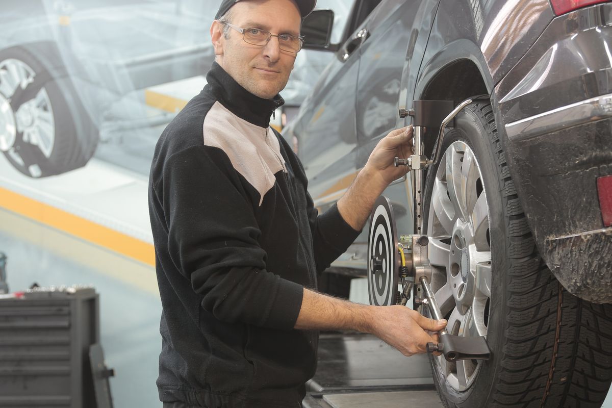 A technician working under a raised vehicle during a scheduled repair