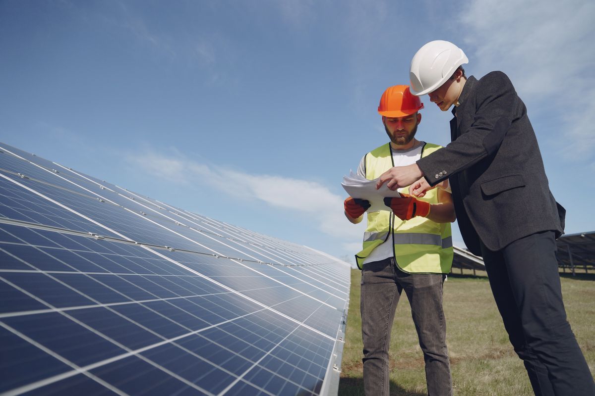 Two tradespeople in hard hats reviewing paperwork together on a job site